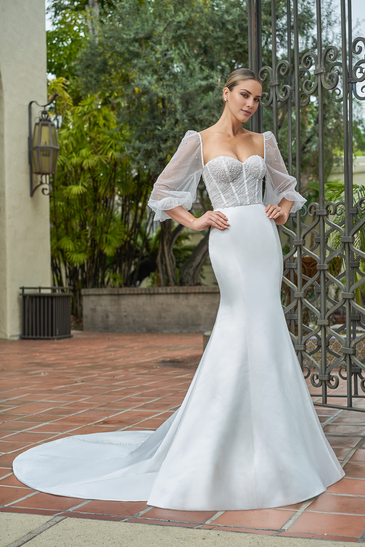 Vestido de novia de satén entallado, con mangas abullonadas transparentes y largo hasta el suelo.