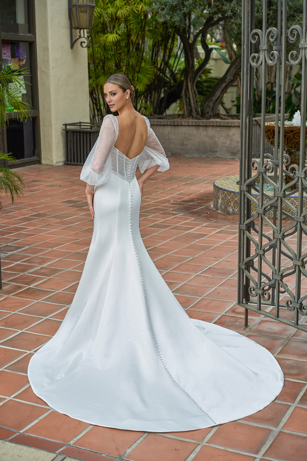 Vestido de novia de satén entallado, con mangas abullonadas transparentes y largo hasta el suelo.