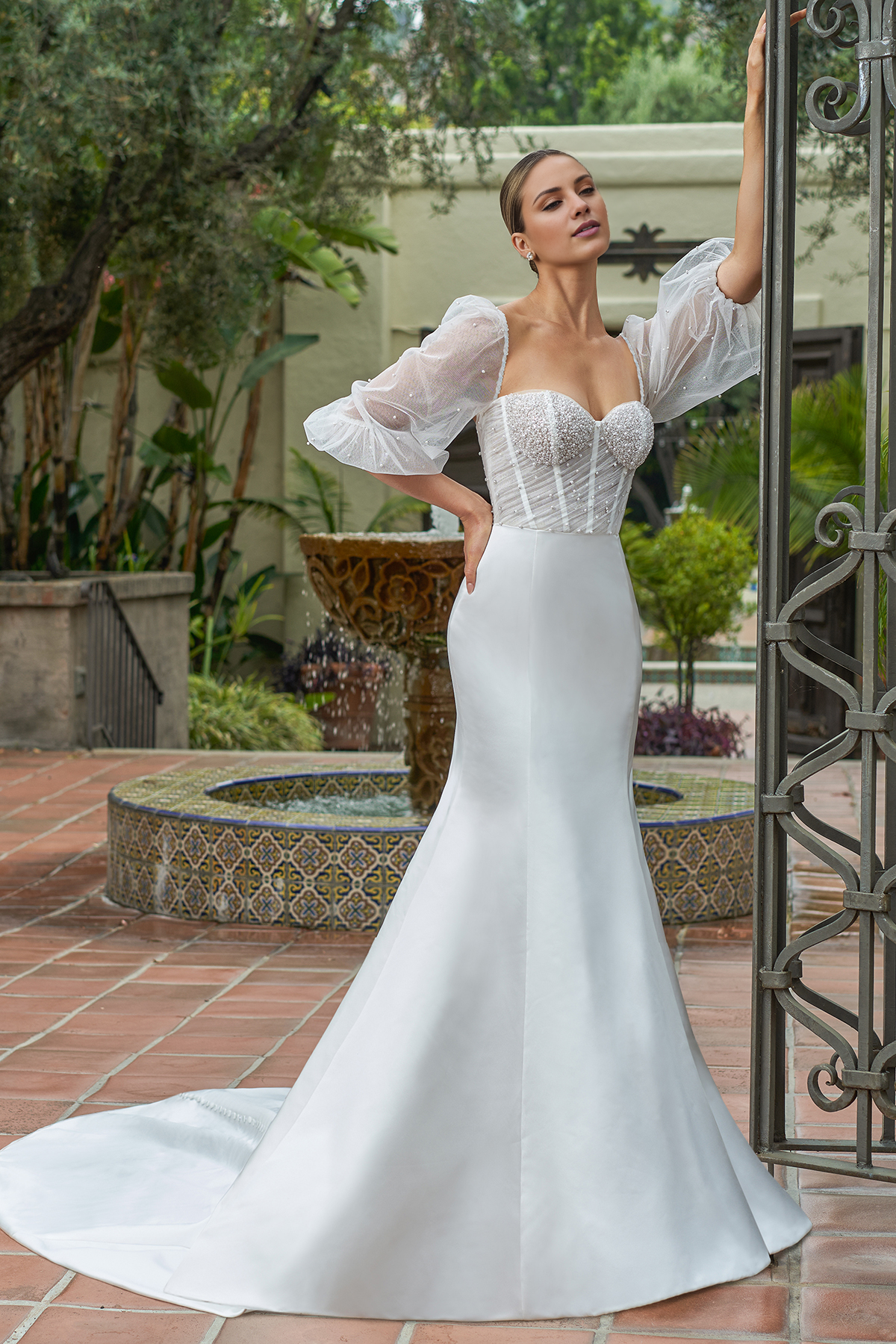 Vestido de novia de satén entallado, con mangas abullonadas transparentes y largo hasta el suelo.