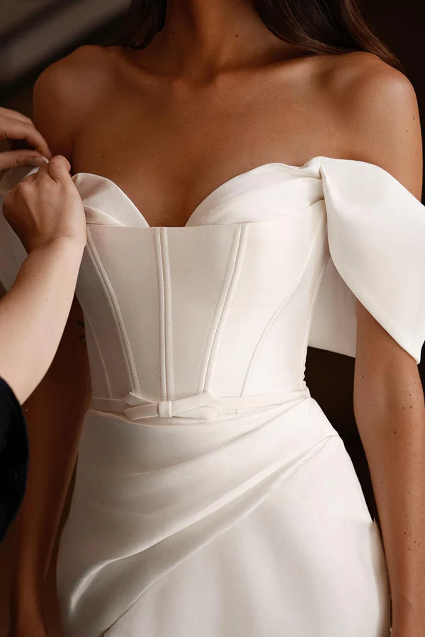 Vestido de novia minimalista de satén, corte entallado, hombros descubiertos y abertura lateral