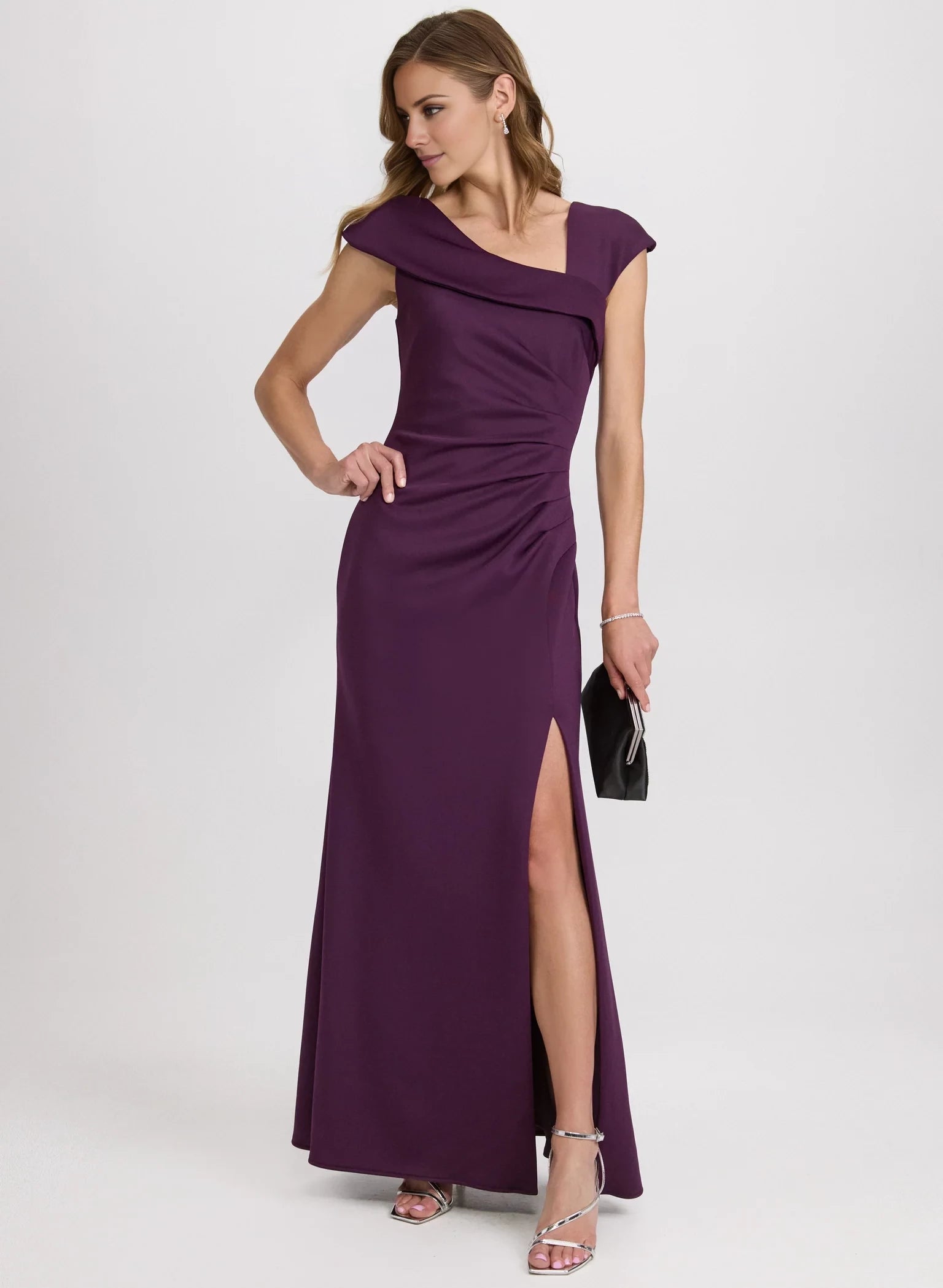 Vestido de fiesta sin mangas con escote asimétrico, detalles plisados, espalda expuesta, abertura lateral y largo hasta el suelo. 