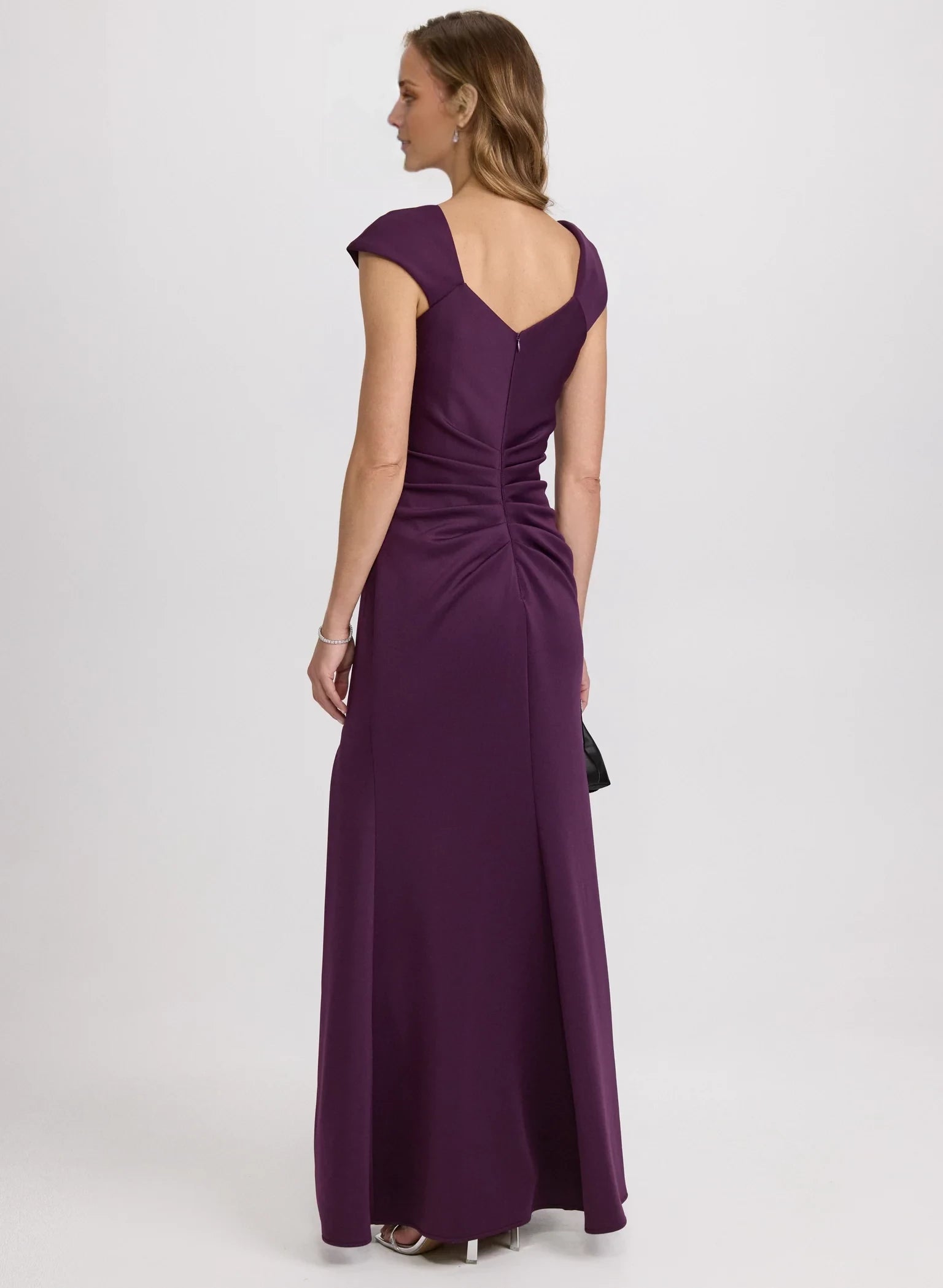 Vestido de fiesta sin mangas con escote asimétrico, detalles plisados, espalda expuesta, abertura lateral y largo hasta el suelo. 