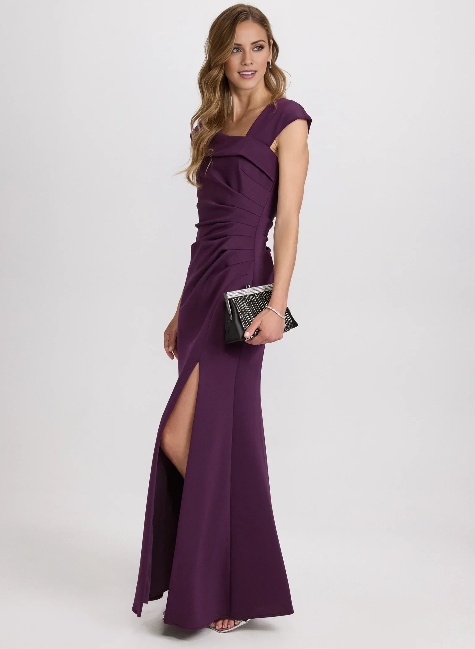 Vestido de fiesta sin mangas con escote asimétrico, detalles plisados, espalda expuesta, abertura lateral y largo hasta el suelo. 