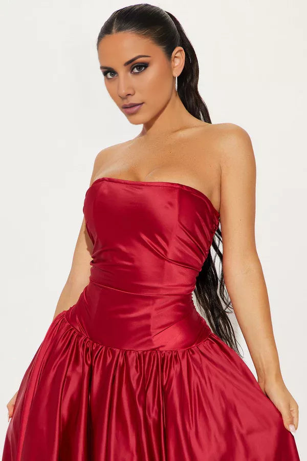 Vestido de noche largo hasta el suelo, sin mangas, sin tirantes, con cuello al descubierto y espalda descubierta, con detalles plisados. 
