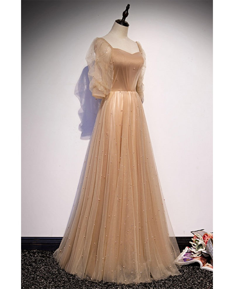 Elegante y noble vestido de noche color champán de manga corta con cuentas de tul, tirantes sin espalda color champán y largo hasta el suelo.