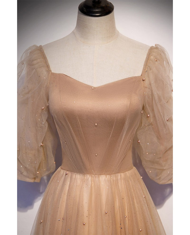 Elegante y noble vestido de noche color champán de manga corta con cuentas de tul, tirantes sin espalda color champán y largo hasta el suelo.