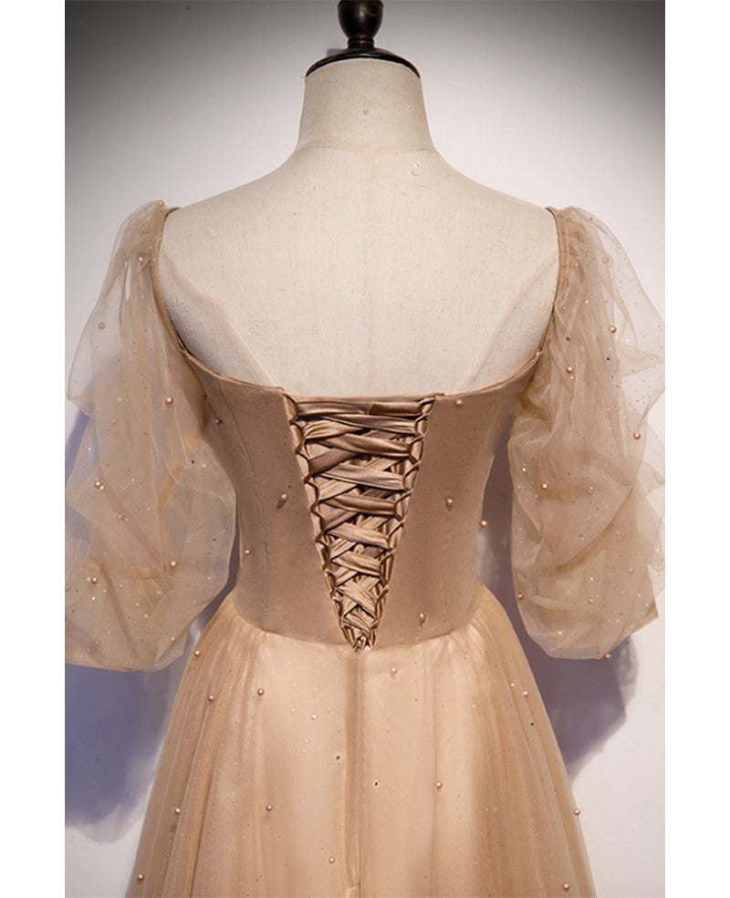 Elegante y noble vestido de noche color champán de manga corta con cuentas de tul, tirantes sin espalda color champán y largo hasta el suelo.