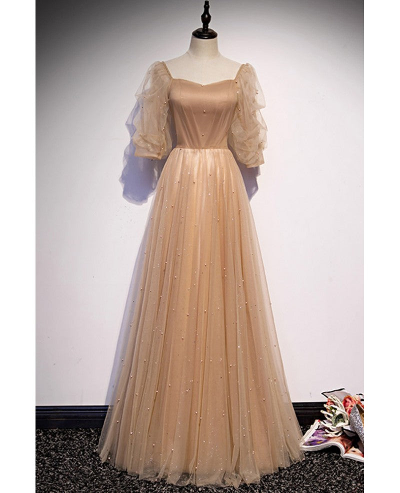 Elegante y noble vestido de noche color champán de manga corta con cuentas de tul, tirantes sin espalda color champán y largo hasta el suelo.