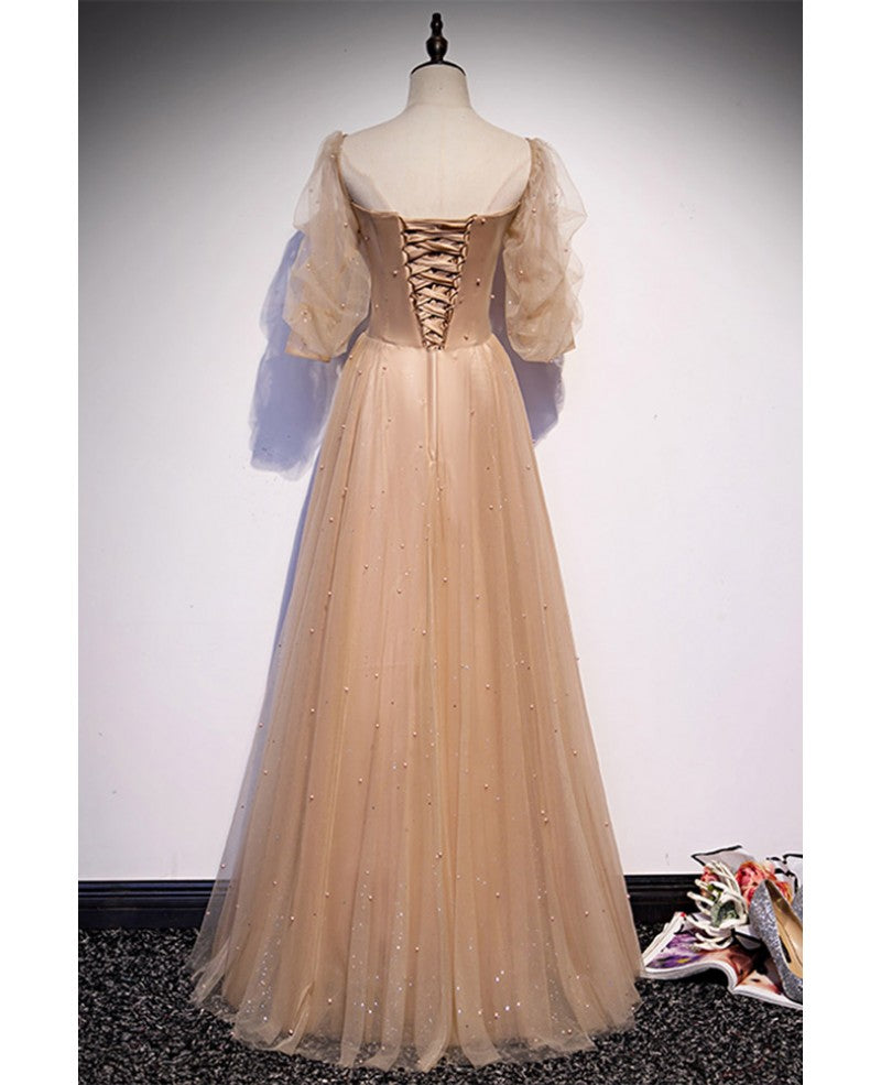 Elegante y noble vestido de noche color champán de manga corta con cuentas de tul, tirantes sin espalda color champán y largo hasta el suelo.