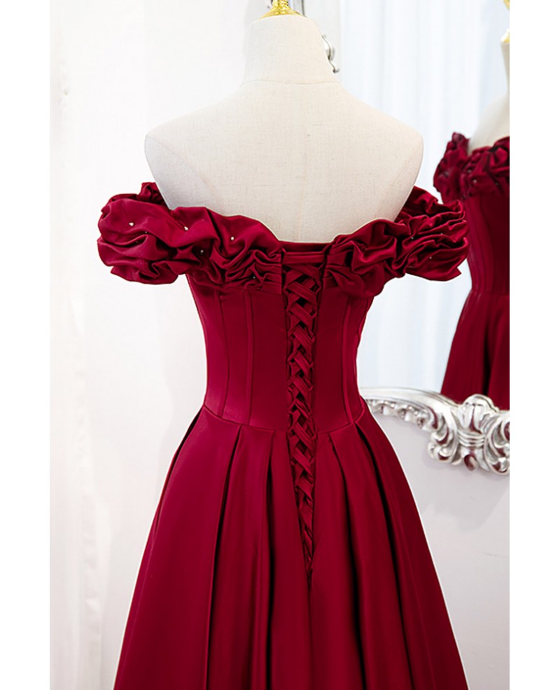 Vestido de fiesta noble y elegante de color rojo vino, sin mangas, con hombros descubiertos, cuentas, tirantes sin espalda en forma de A y dobladillo con volantes hasta el suelo.