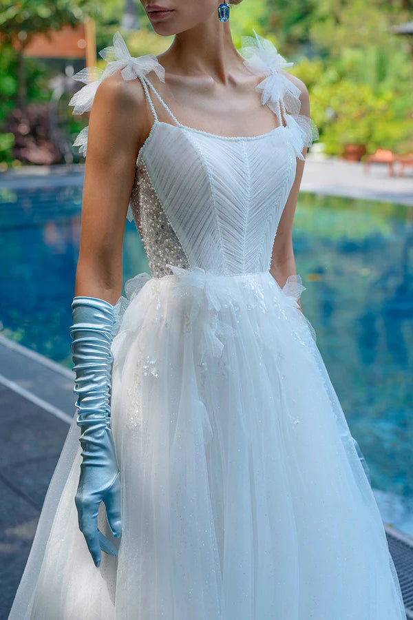 A simple wedding dress with thin shoulder straps, spoonful beads, and a single thread